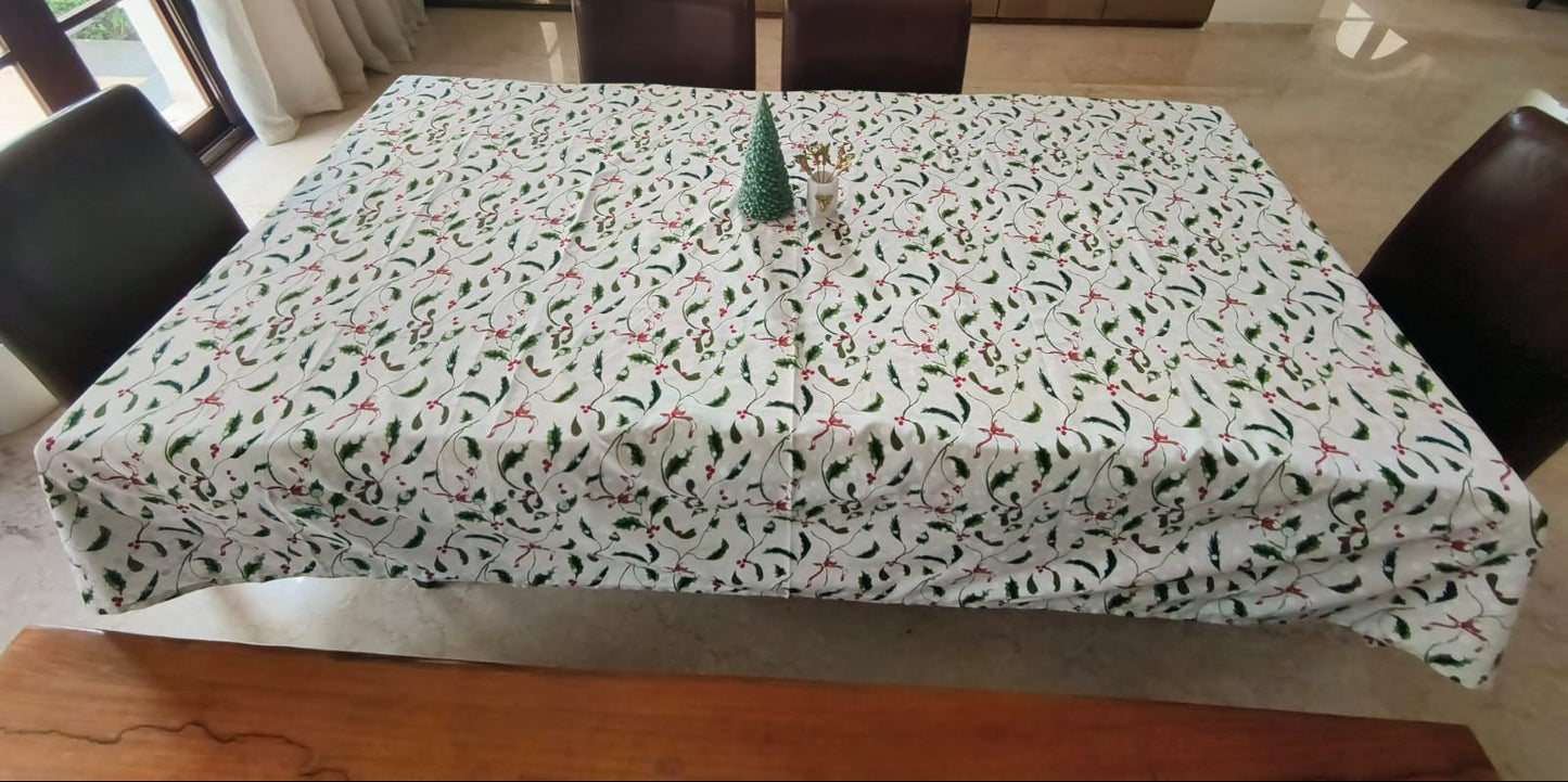 Dining table with a patterned tablecloth in a room with chairs and a view of another room.
