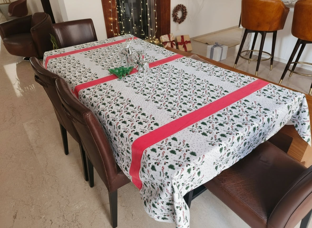 Dining table with a patterned tablecloth and red trim in a room with chairs and a rug.