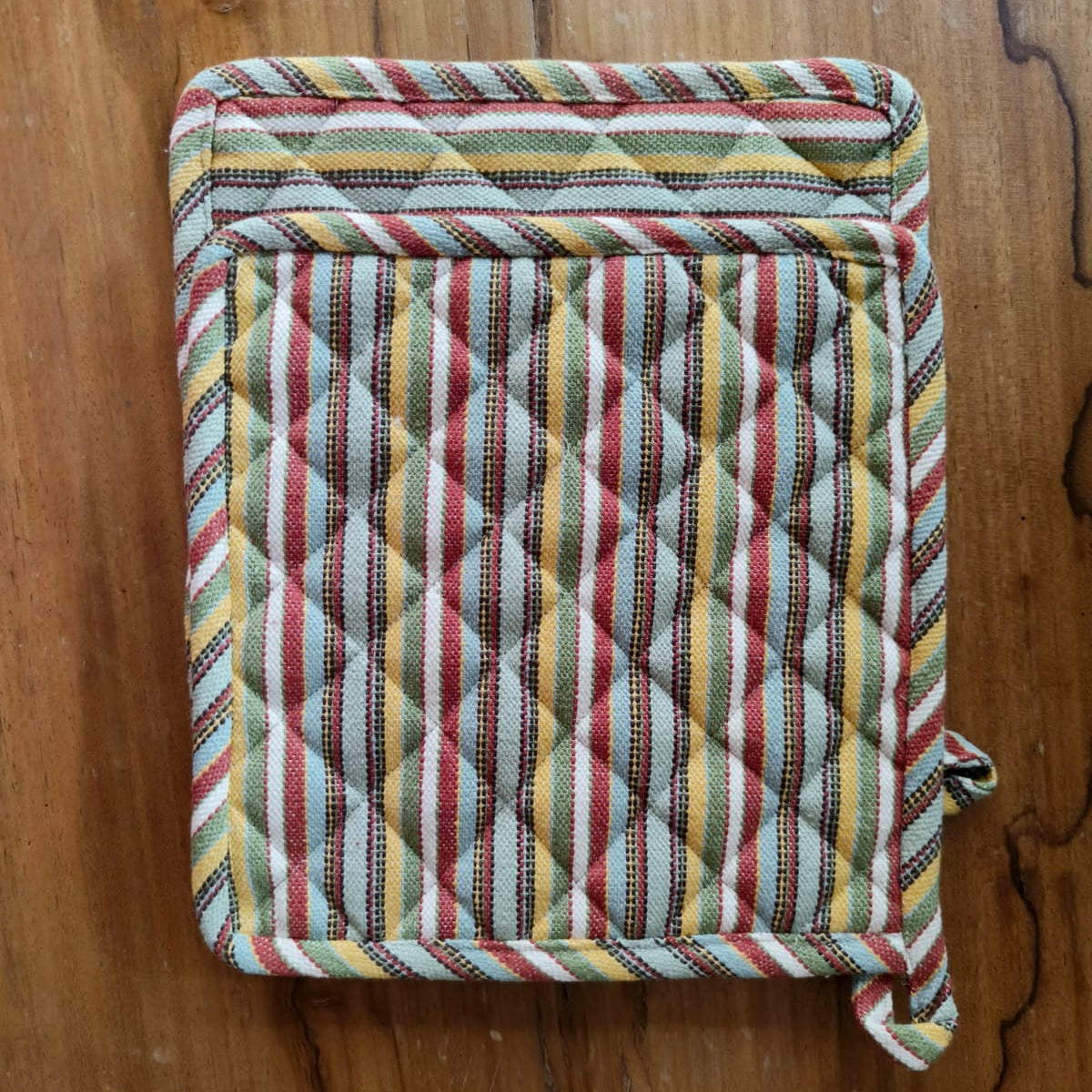 Multicolored quilted pot holder on a wooden surface