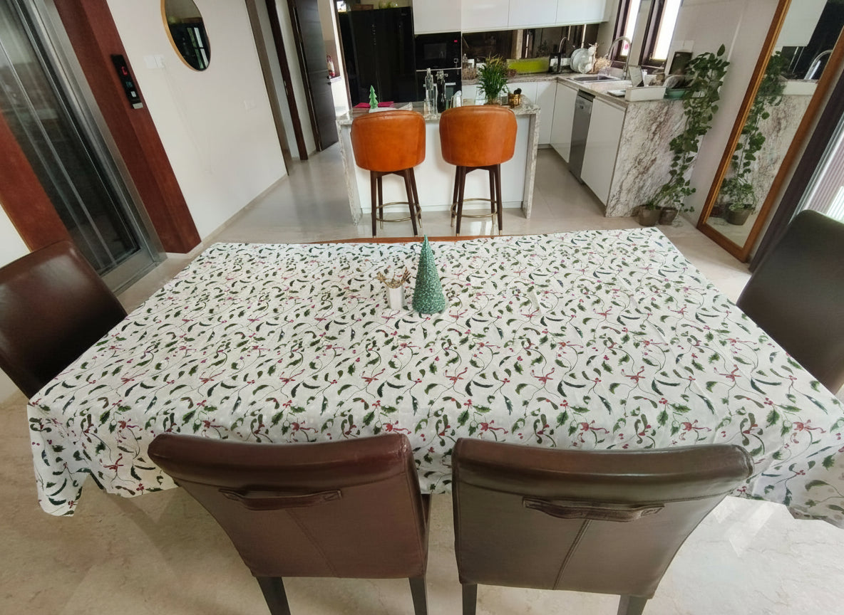 Dining area with a table covered by a patterned tablecloth and chairs.