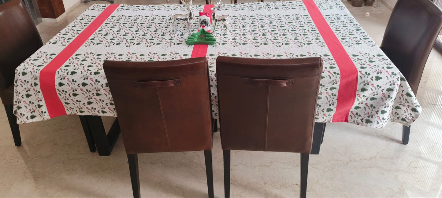 Dining table with a patterned tablecloth and red stripes, surrounded by chairs in a kitchen.