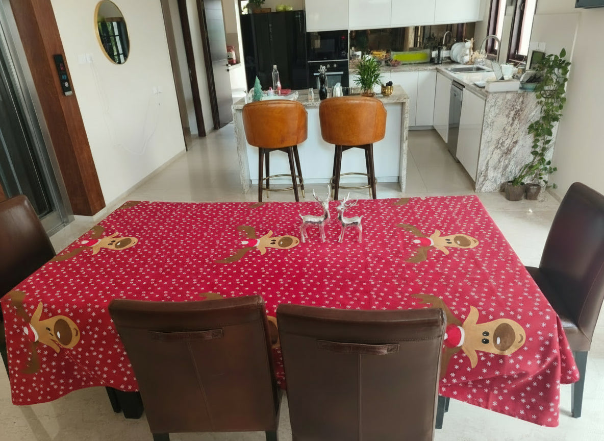 Dining table with a red tablecloth featuring gingerbread men and white polka dots, set in a kitchen.