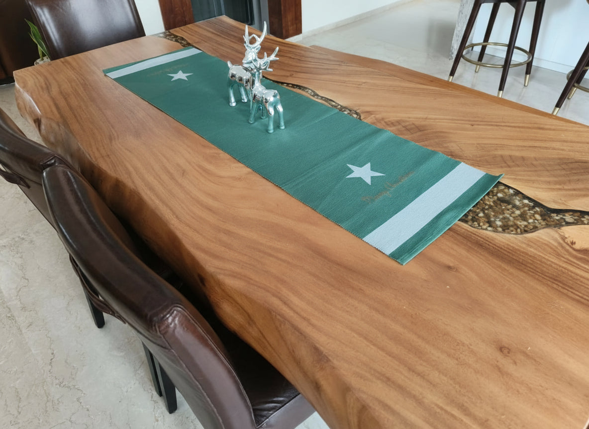 Wooden dining table with a green runner and deer figurines, surrounded by brown chairs.